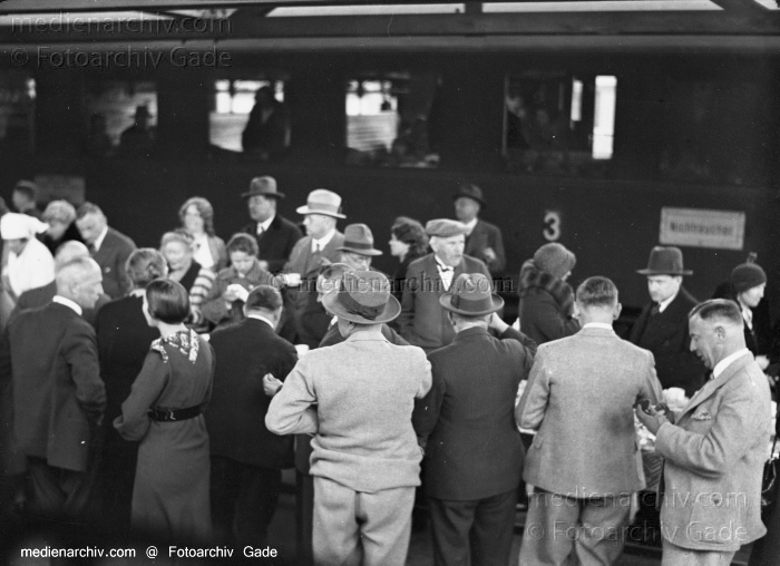 1932. Auf einem Bahnhof
1932. Auf einem Bahnsteig. Vor dem Eisenbahnwaggon steht ein langer Tisch mit Tassen. Die Menschen haben Tassen in der Hand. Am Zug steht unscharf 'Nichtraucher'
Schlüsselwörter: 1932;Africa;Afrika;Bahnhof;Eisenbahn;Fahrgäste