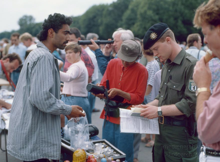 Berlin. Brandenburger Tor. Ein Polizist prüft die Papiere eines ambulanten Händlers
23. 6. 1991. Berlin. Mitte. Brandenburger Tor. Brandenburg Gate. Ein Polizist prüft die Papiere eines ambulanten Händlers mit Ostblocksouvenirs.
Schlüsselwörter: Berlin;Brandenburg Gate;Brandenburger Tor;Deutschland;Germany;Händler;Mitte;1991;Polizei