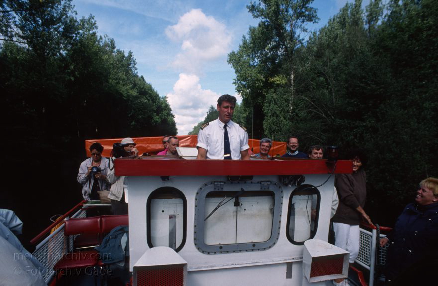 Auf dem Wasser von Röbel nach Rheinsberg
30. 8. 1994. Mecklenburg-Vorpommern. Der Kapitän auf einem Ausflugsdampfer auf dem Müritz-Havel-Kanal. Mecklenburger Seenplatte. Die Brückenkabine wurde wegen der besseren Sicht und einiger Brücken über dem Kanal abgesenkt.   (Dampferfahrt von Röbel nach Rheinsberg.)
Schlüsselwörter: Ausflugsdampfer;Dampfer;Dampferfahrt;Deutschland;Fahrgastschiffe;Germany;Mecklenburg-Vorpommern;Mecklenburg-Western Pomerania;Meckpom;Meckpomm;Mekelnborg-Vörpommern;Müritz;Röbel;Schiffe;Schiffsführer;See;1994;Steuerstand