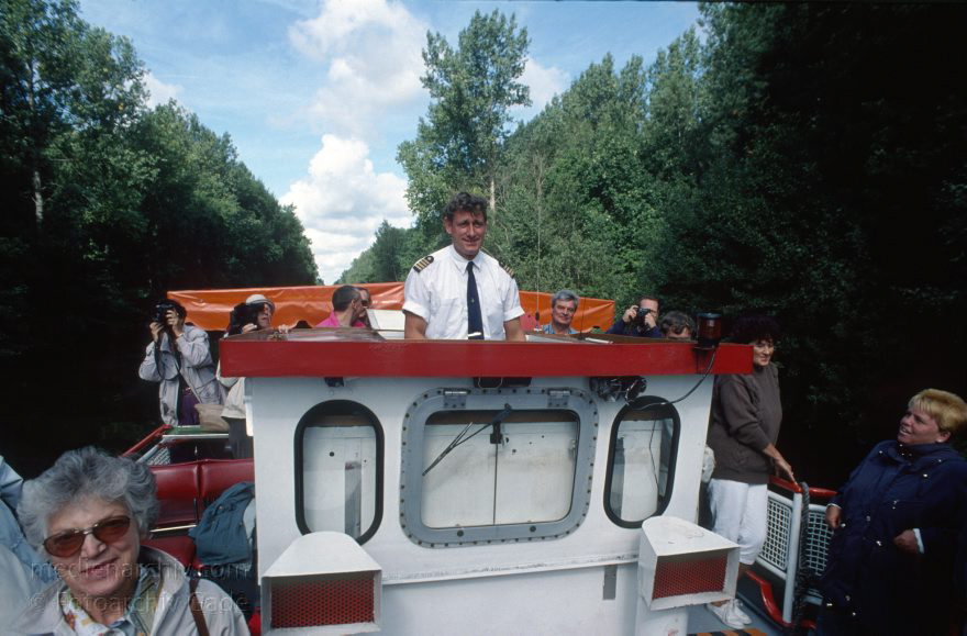 Auf dem Wasser von Röbel nach Rheinsberg
30. 8. 1994. Mecklenburg-Vorpommern. Der Kapitän auf einem Ausflugsdampfer auf dem Müritz-Havel-Kanal. Mecklenburger Seenplatte. Die Brückenkabine wurde wegen der besseren Sicht und einiger Brücken über dem Kanal abgesenkt.   (Dampferfahrt von Röbel nach Rheinsberg.)
Schlüsselwörter: Ausflugsdampfer;Dampfer;Dampferfahrt;Deutschland;Fahrgastschiffe;Germany;Mecklenburg-Vorpommern;Mecklenburg-Western Pomerania;Meckpom;Meckpomm;Mekelnborg-Vörpommern;Müritz;Röbel;Schiffe;Schiffsführer;See;1994;Steuerstand