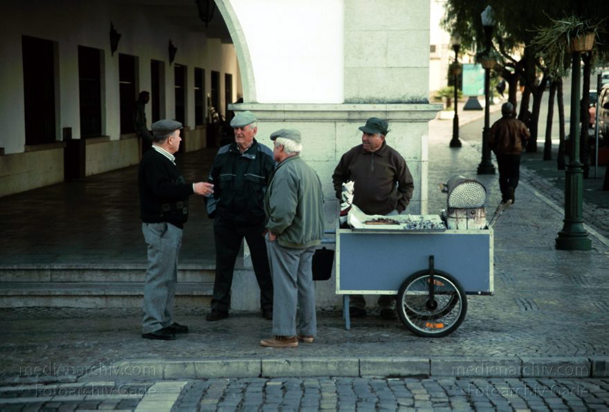 Portugal. Tavira
November 2000. Portugal. Tavira.  Der Maronenröster verkauft heisse Kastanien. Männer an der Straße. Karren.
Schlüsselwörter: 2000;Kastanie;Marone;Portugal;Tavira