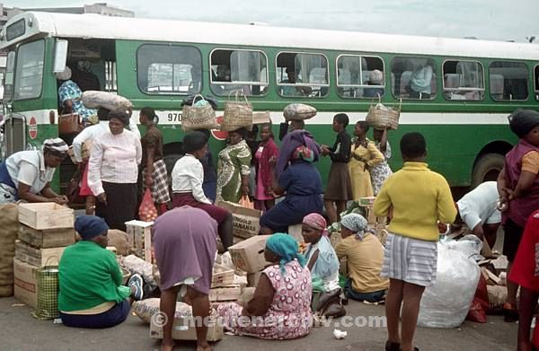 1975. Südafrika. Afrikaner mit Gepäck an einer Bushaltestelle. Autobus. Last auf dem Kopf