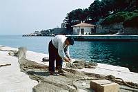 1959. Kroatien ( Jugoslawien)  Insel Lošinj. Losinj  (deutsch veraltet: Lötzing. italienisch: Lussino)  Kroatische Insel in der Adria. Ein Fischer flickt seine Netze im Hafen. Croatia (Yugoslavia )