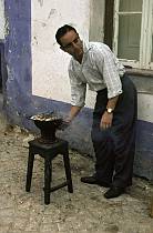 1963. Portugal. Mann mit Sardinen auf einem Grill. Fische