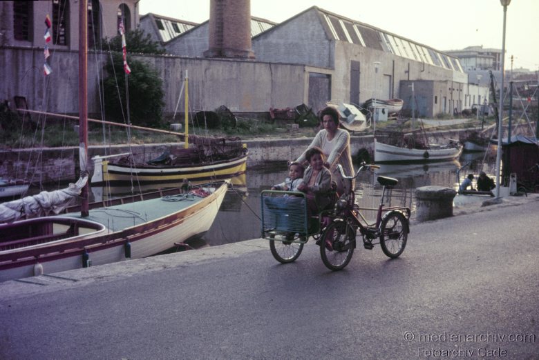 1976. Niedersachsen. Ostfriesland. Insel Föhr. Fischeboote. Frau auf einem Fahrrad