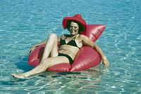 1975. Spanien. Baleren. Menorca. Urlauberin. Frau beim Baden treibend auf einem aufblasbaren Stuhl. Bikini