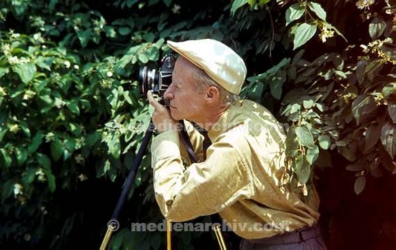 Ein Mann fotografiert mit einer Kamera auf einem Stativ. Fotograf
