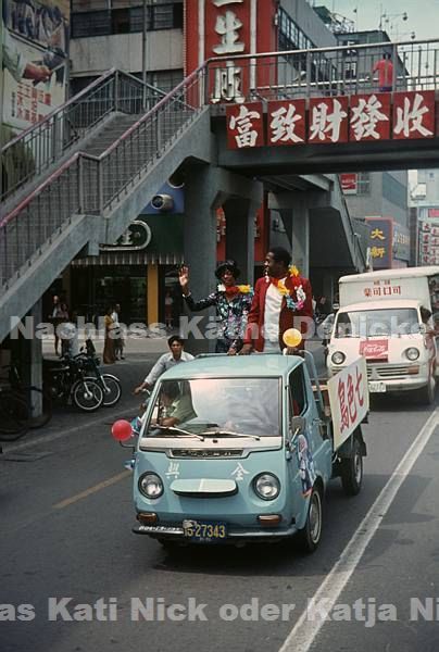 1974. Asien. Hongkong. The World Surprise Show. Die Darsteller fahren in offenen Autos und präsentieren sich.