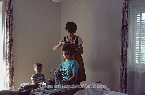 1969. Berlin. Eine Frau schneidet einer anderen Frau die Haare